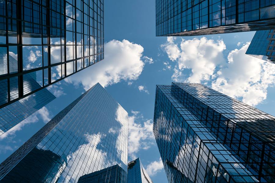 Glass office towers seen from below against a blue sky